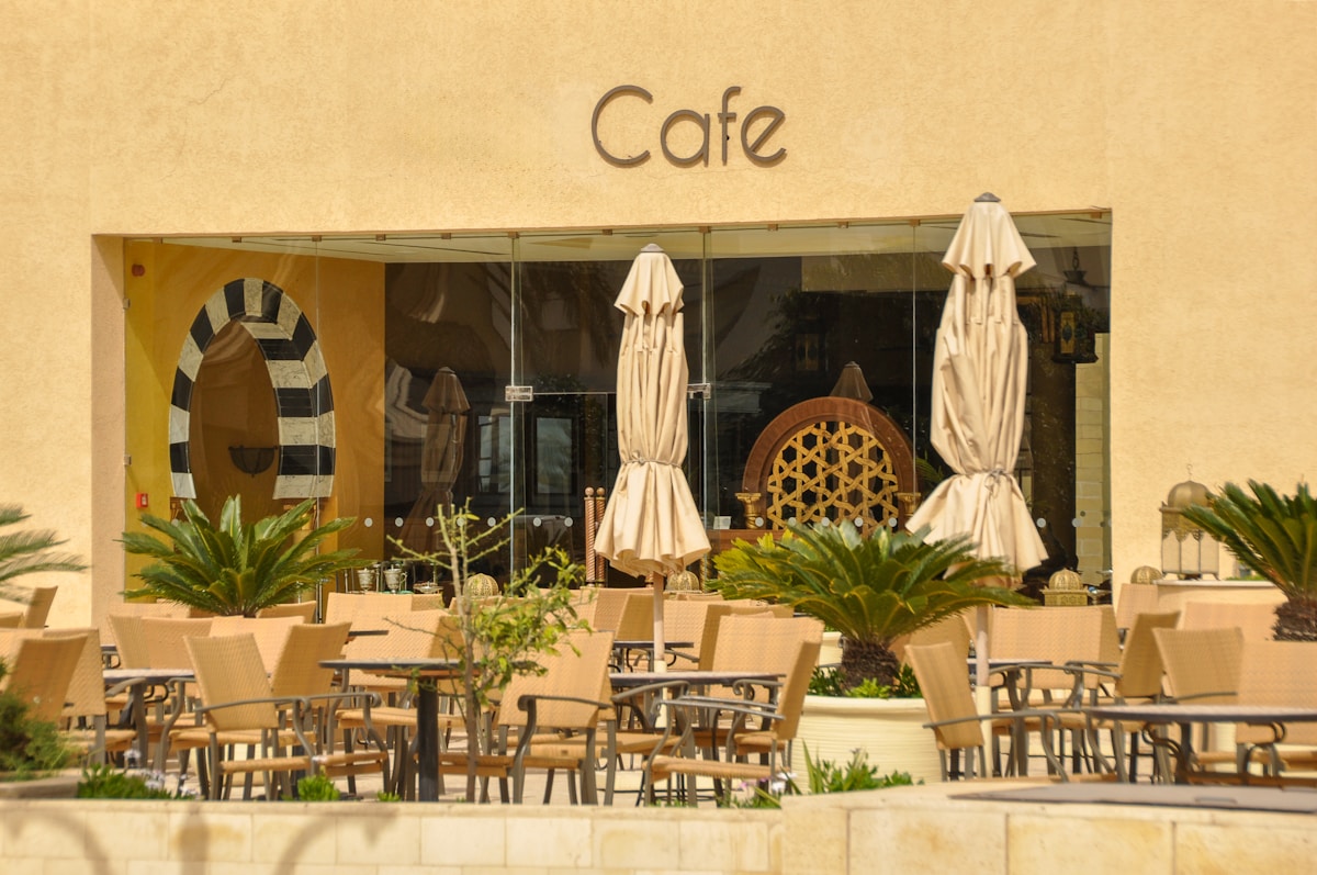 Outdoor café terrace with beige umbrellas under a yellow Mediterranean facade, Tunis, Tunisia