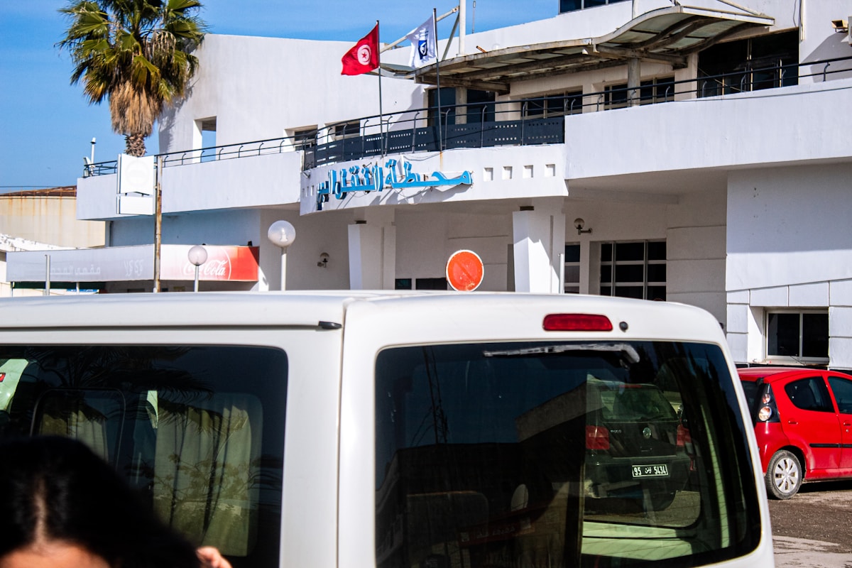 A louage shared taxi van at a station in Tunisia with the Tunisian flag flying above