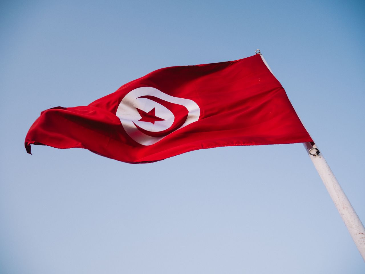 Tunisia national flag waving against a clear blue sky - public holidays guide for visitors