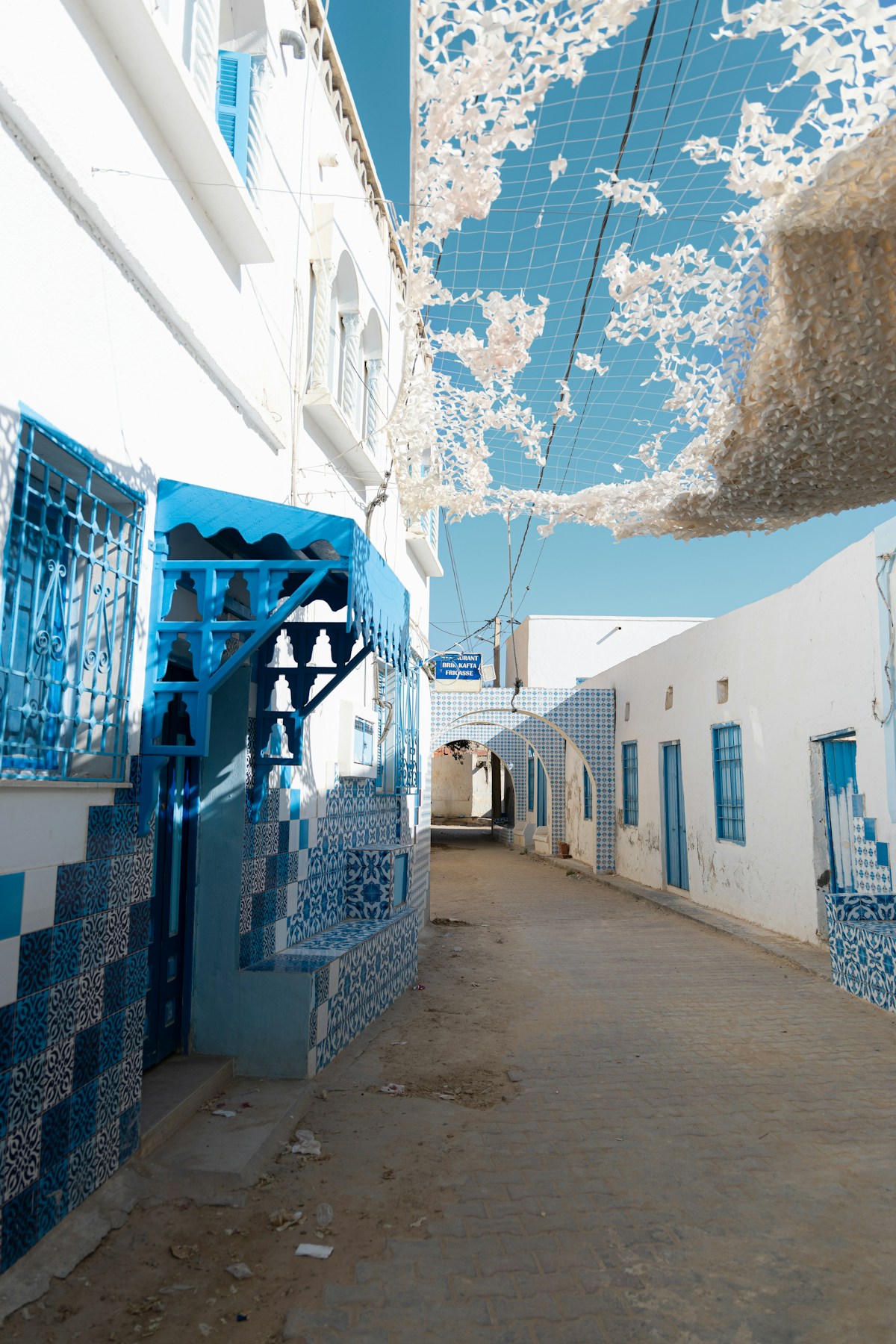 A whitewashed Tunisian street with blue and white tilework and decorative arched gateway on the Cap Bon peninsula