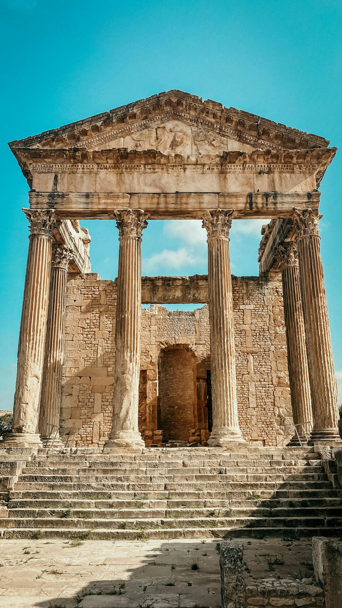 The Capitol temple at Dougga Roman ruins — columns and pediment under a clear blue sky, Tunisia