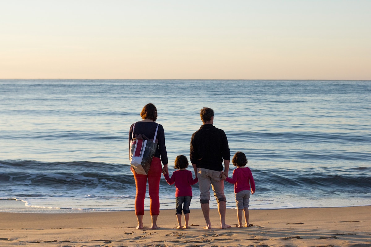 Famille de quatre personnes regardant la mer au coucher de soleil sur une plage méditerranéenne