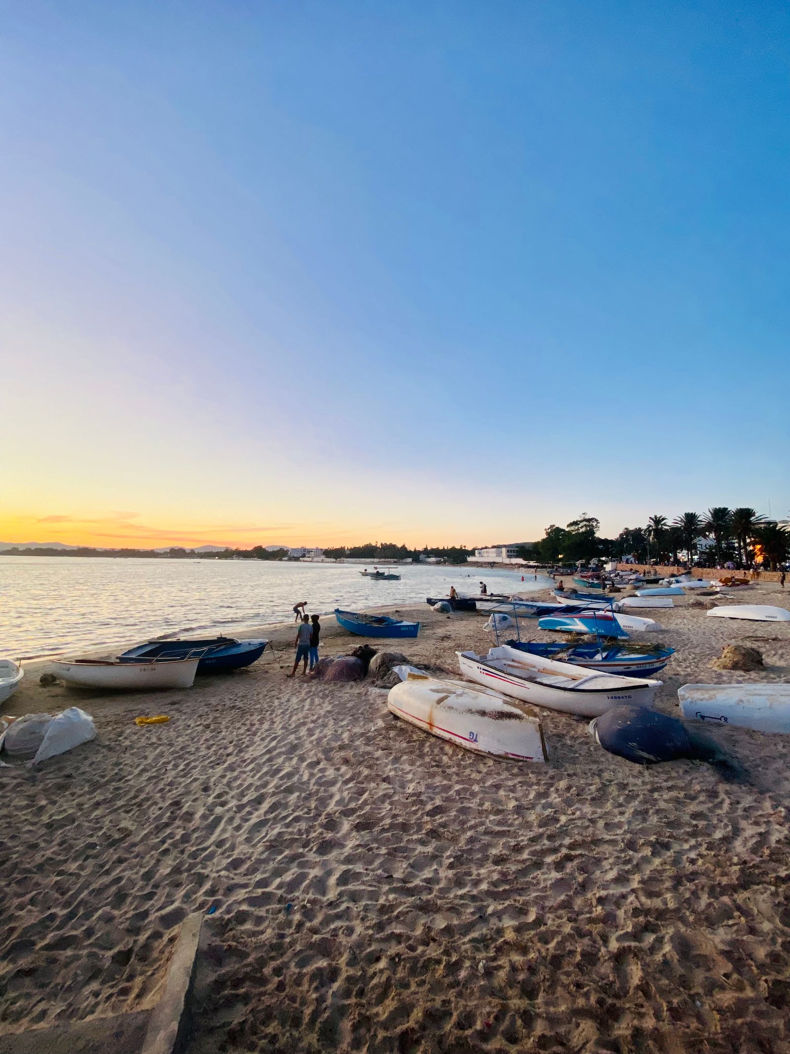 Small fishing boats on a sandy beach at sunset near Hammamet, Tunisia