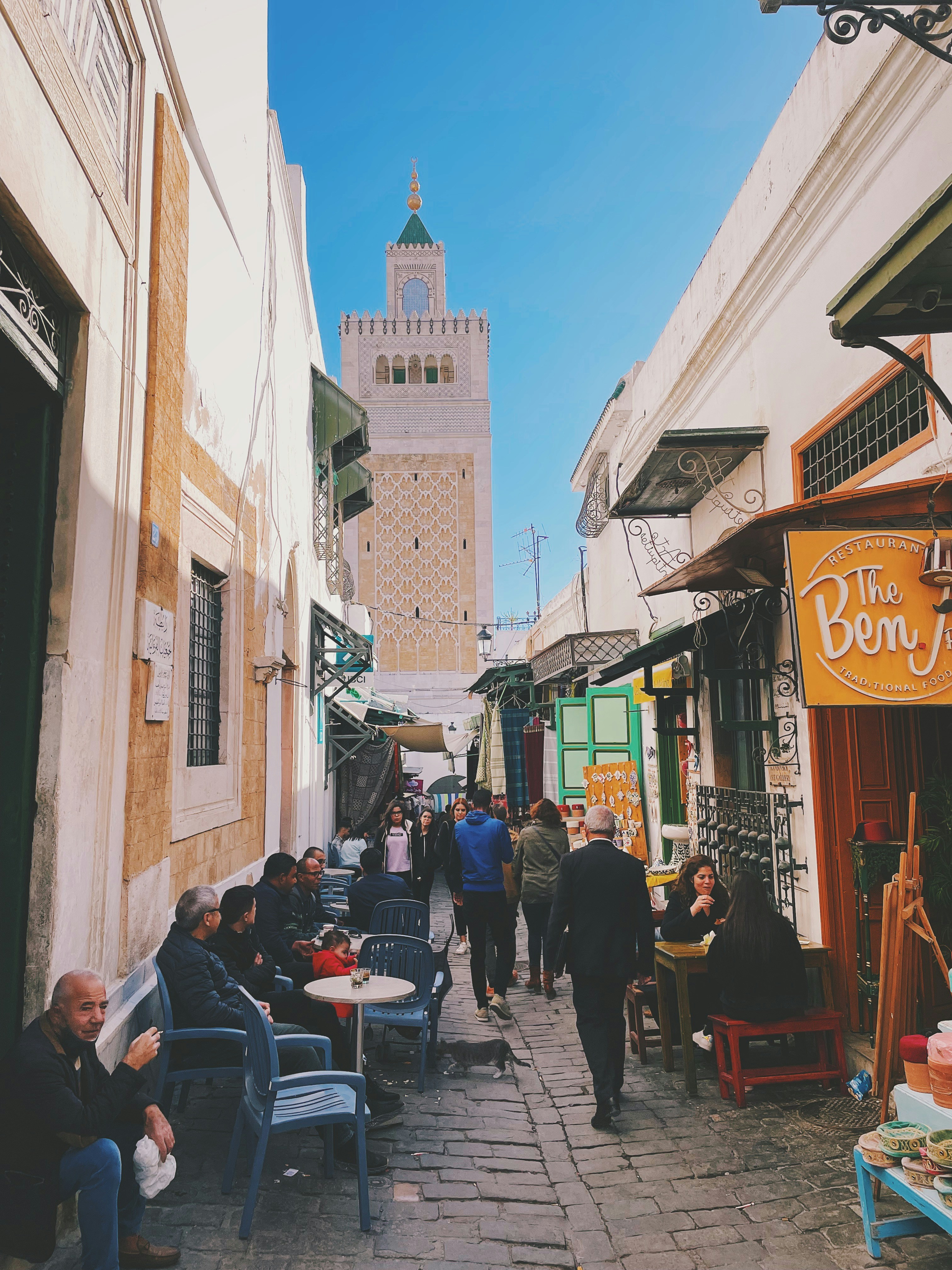 Busy souk alley in the medina of Tunis with the Zitouna mosque minaret in the background