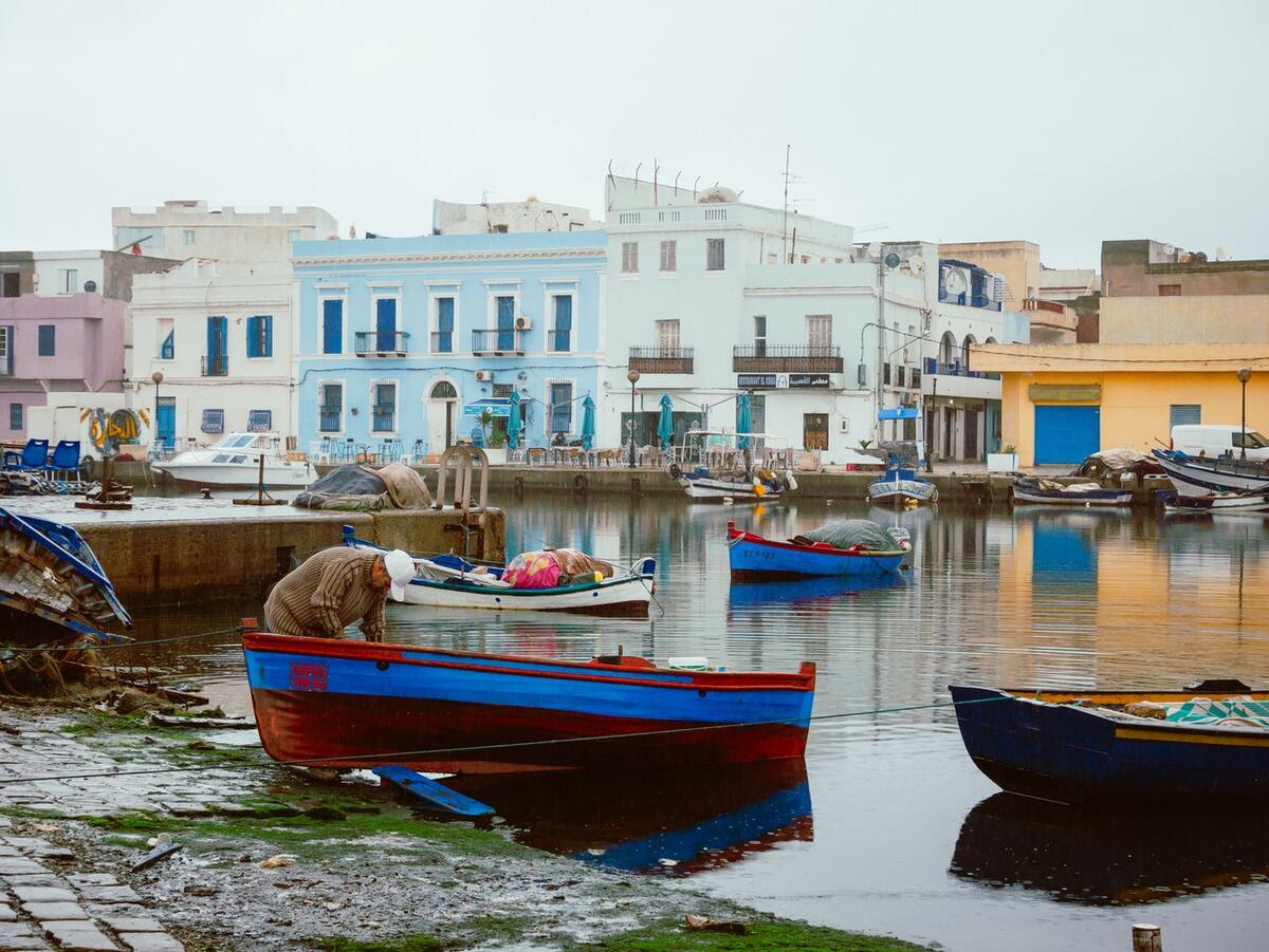 Colourful fishing boats and pastel buildings reflected in the Bizerte harbour, Tunisia