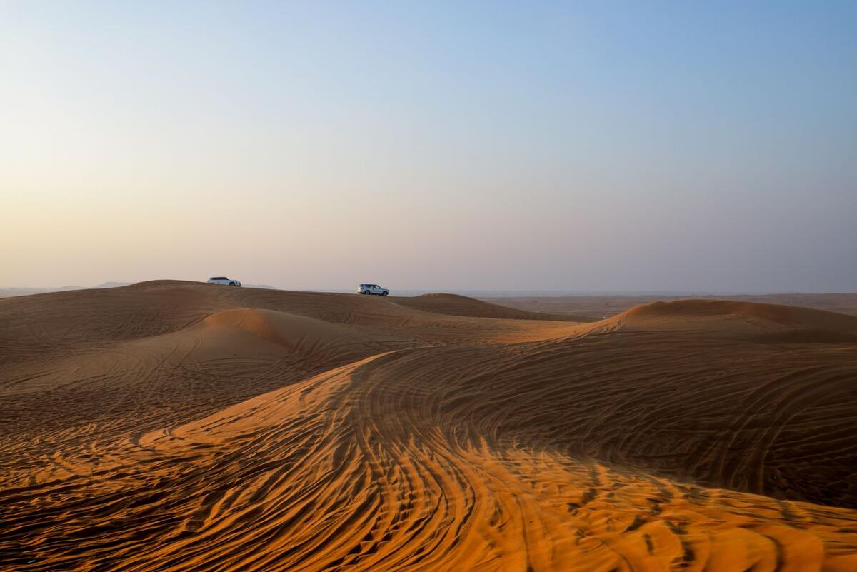 Off-road vehicles crossing Sahara dunes at dawn, Tunisia