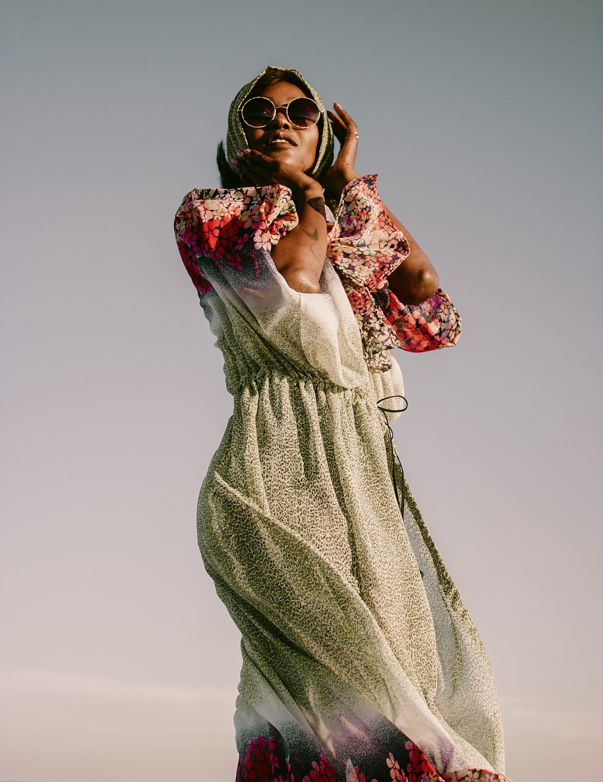 A Tunisian woman in traditional floral dress against the desert sky, Tunisia