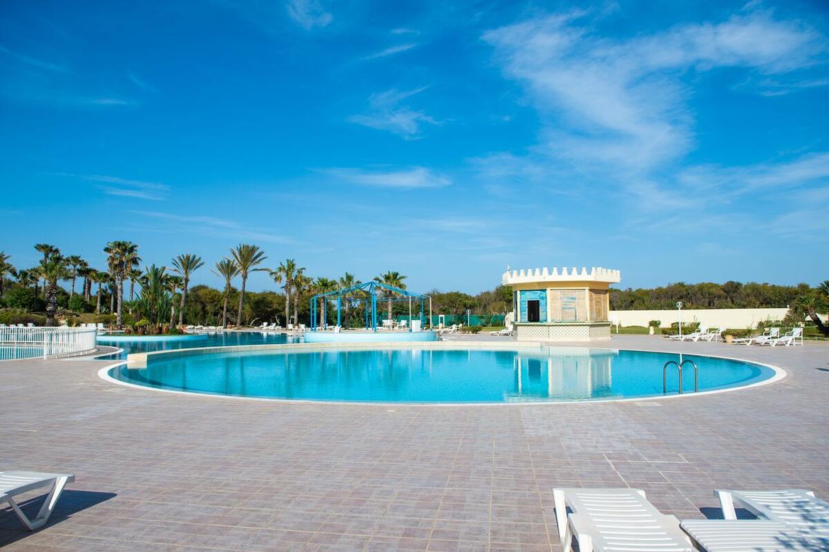 Piscine ronde d'hôtel avec transats et palmiers dans un resort tunisien